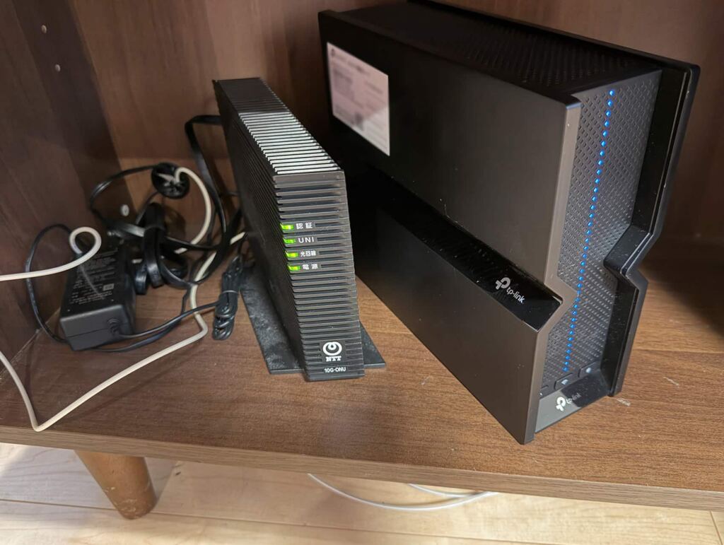 テレビ台の棚の中にONUと並べて設置したTP-Link Archer BE700
