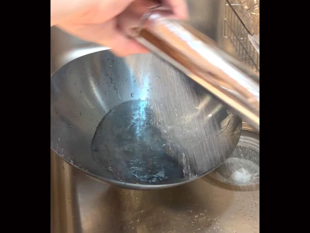水としゅろたわしで中華鍋を洗う
